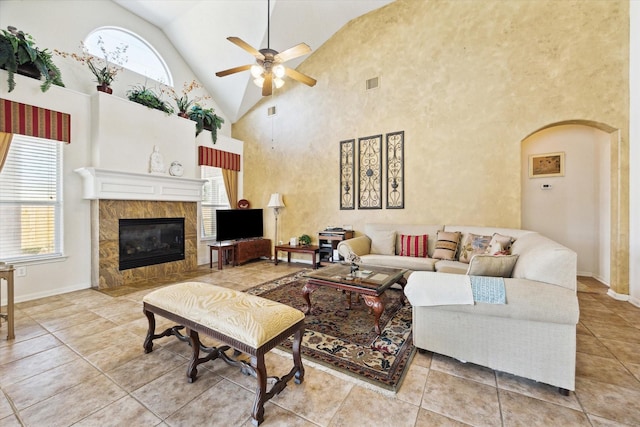 tiled living room with plenty of natural light, a ceiling fan, visible vents, and a tile fireplace