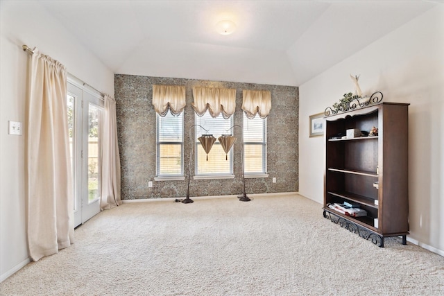 unfurnished dining area featuring a raised ceiling, carpet flooring, baseboards, and lofted ceiling