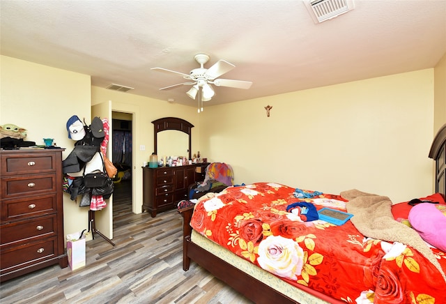 bedroom featuring visible vents, light wood-style flooring, a textured ceiling, and ceiling fan