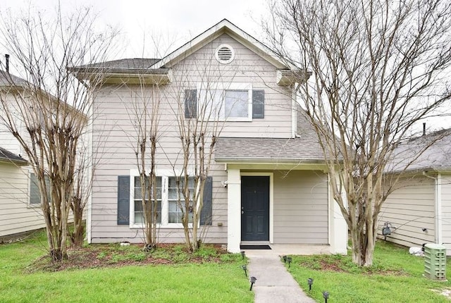 traditional home featuring roof with shingles and a front lawn