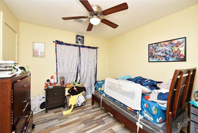 bedroom with a ceiling fan, wood finished floors, and visible vents