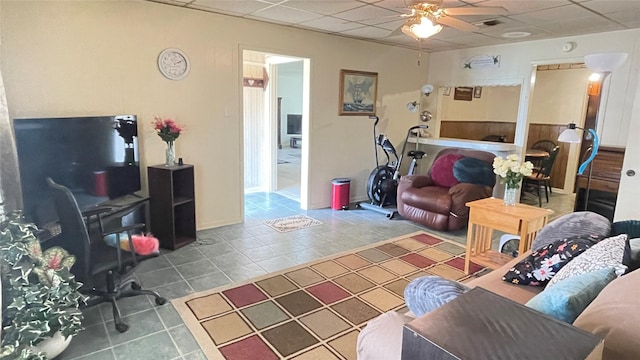 living area with tile patterned flooring, a drop ceiling, and ceiling fan