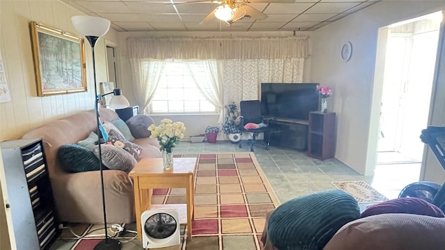 living room featuring a drop ceiling, a ceiling fan, and tile patterned flooring