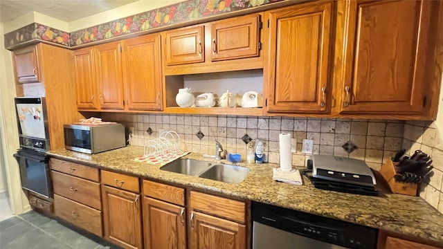 kitchen with tasteful backsplash, appliances with stainless steel finishes, light stone counters, and a sink