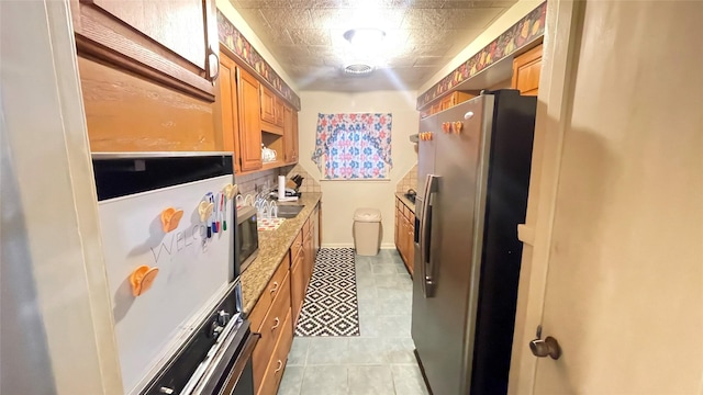 kitchen featuring visible vents, brown cabinets, a sink, appliances with stainless steel finishes, and baseboards