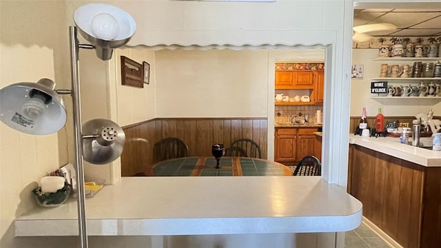 dining room featuring a wainscoted wall, a paneled ceiling, wooden walls, and tile patterned flooring