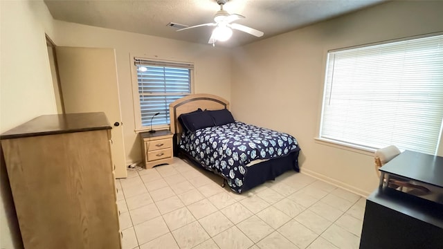 bedroom featuring visible vents, a textured ceiling, light tile patterned flooring, baseboards, and ceiling fan