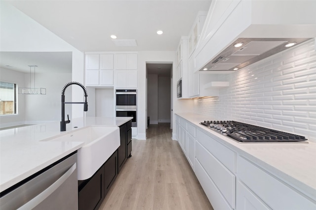 kitchen featuring a sink, decorative backsplash, extractor fan, appliances with stainless steel finishes, and white cabinetry