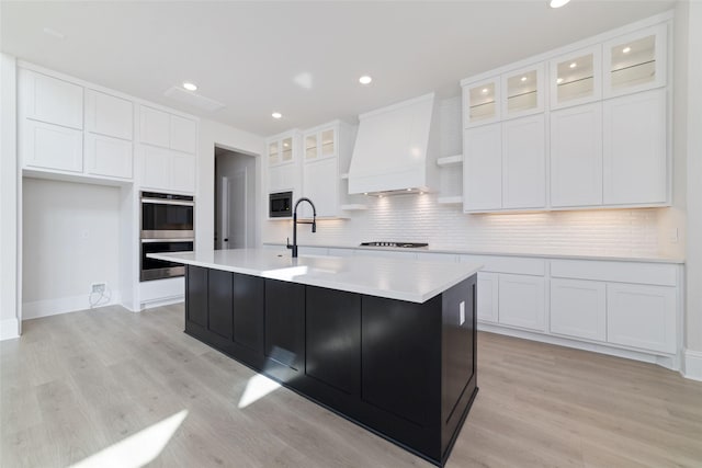 kitchen featuring premium range hood, gas stovetop, built in microwave, white cabinetry, and double oven