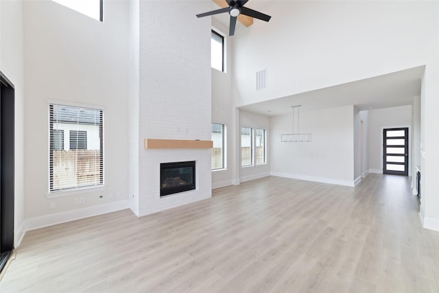 unfurnished living room featuring a ceiling fan, light wood-style floors, a fireplace, and visible vents