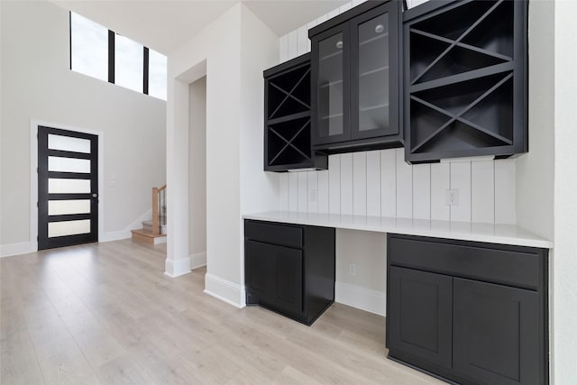 interior space with light wood-type flooring, baseboards, and stairway