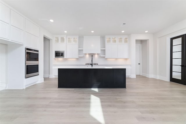 kitchen with tasteful backsplash, appliances with stainless steel finishes, white cabinetry, and light countertops