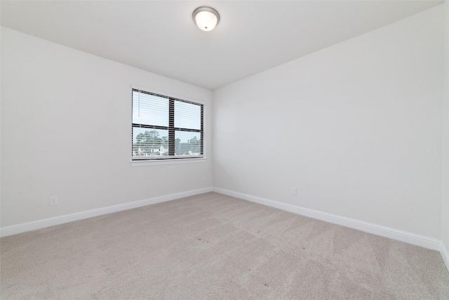 empty room featuring light carpet and baseboards