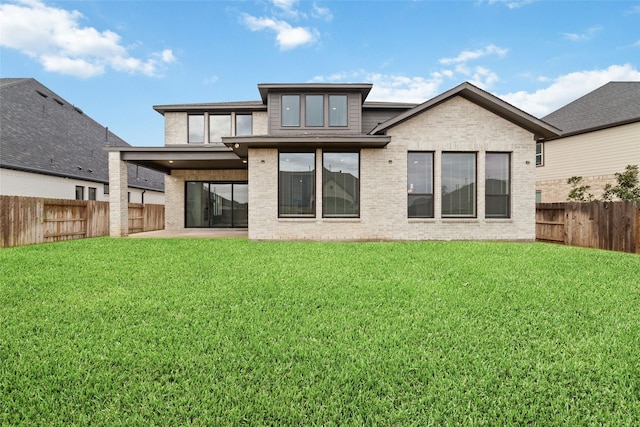 rear view of property with a yard, a patio, brick siding, and a fenced backyard