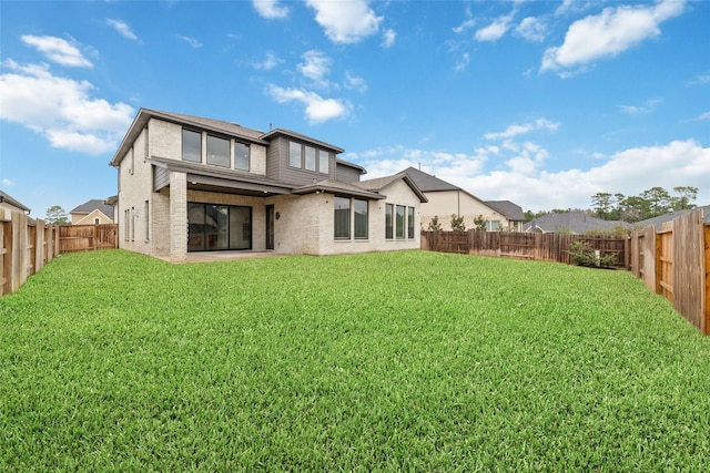 rear view of property featuring brick siding, a lawn, and a fenced backyard