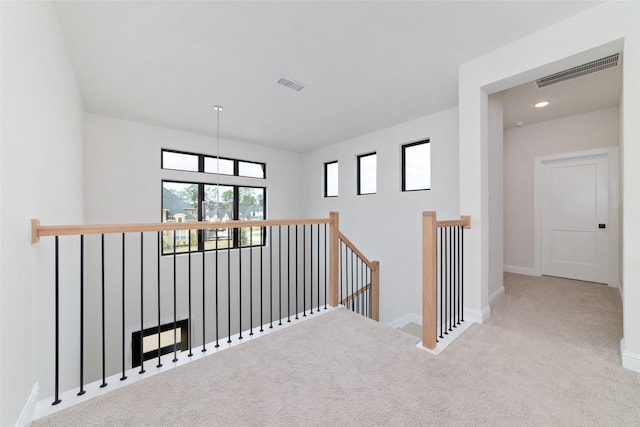 corridor featuring visible vents, an upstairs landing, carpet, and baseboards