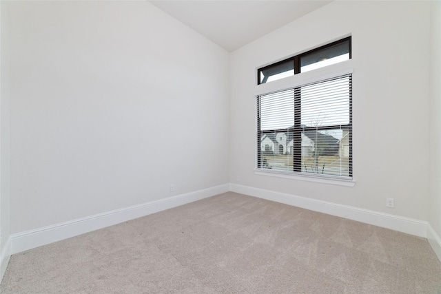 empty room with vaulted ceiling, carpet flooring, and baseboards