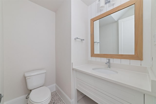 bathroom featuring toilet, vanity, and baseboards