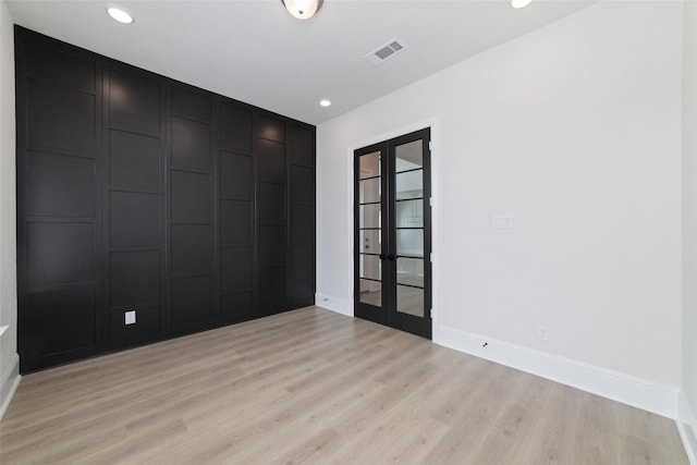 unfurnished room with visible vents, french doors, and light wood-type flooring