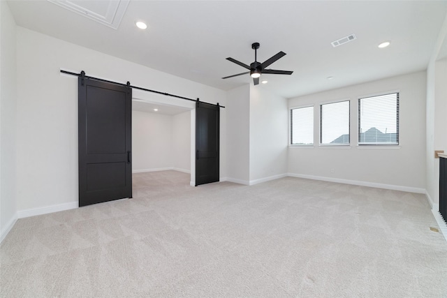 unfurnished bedroom featuring baseboards, visible vents, recessed lighting, light carpet, and a barn door