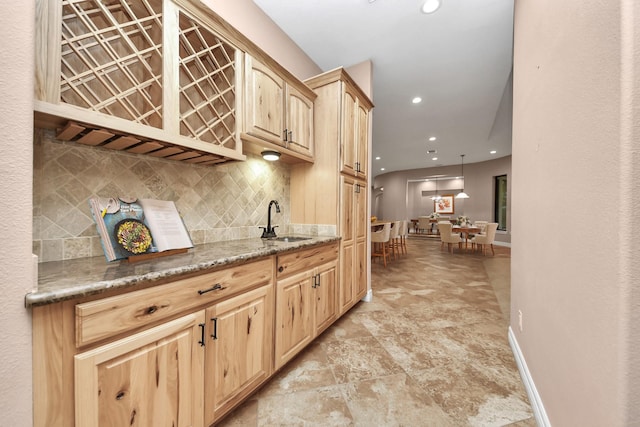 bar featuring stone finish floor, a sink, tasteful backsplash, recessed lighting, and baseboards