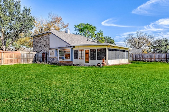 back of house featuring board and batten siding, a sunroom, a chimney, a fenced backyard, and a yard