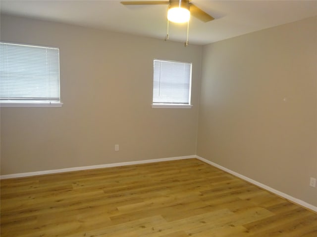 empty room with baseboards, light wood-type flooring, and a wealth of natural light