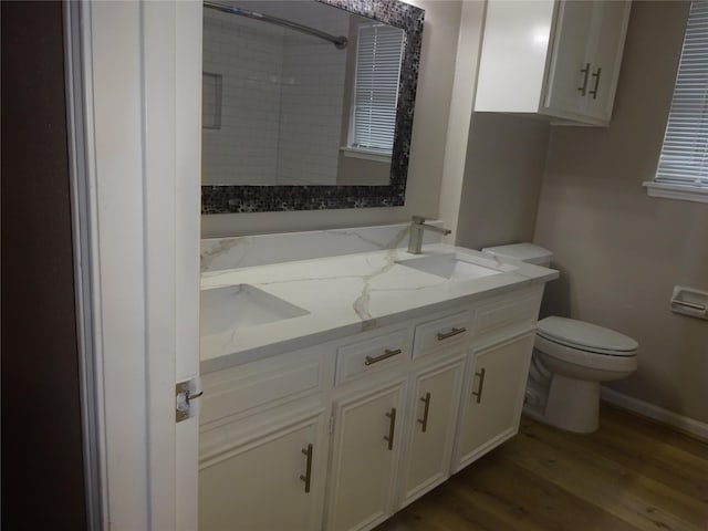 full bathroom featuring vanity, wood finished floors, baseboards, a shower, and toilet