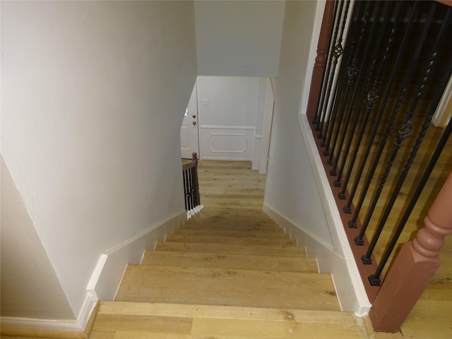 stairs featuring a decorative wall and wood finished floors