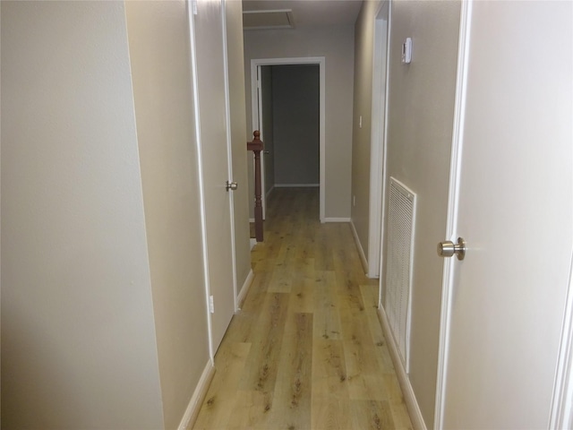 hallway featuring visible vents, baseboards, and light wood-style flooring