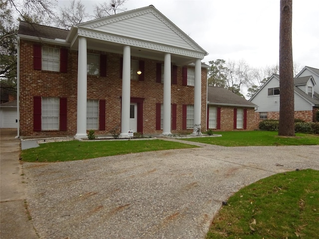 greek revival inspired property with brick siding and a front lawn