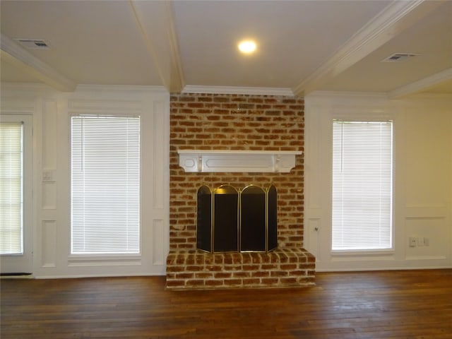 unfurnished living room with a brick fireplace, wood finished floors, visible vents, and ornamental molding