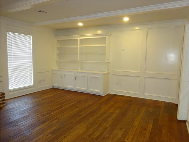 unfurnished room with a decorative wall, crown molding, dark wood-type flooring, and visible vents