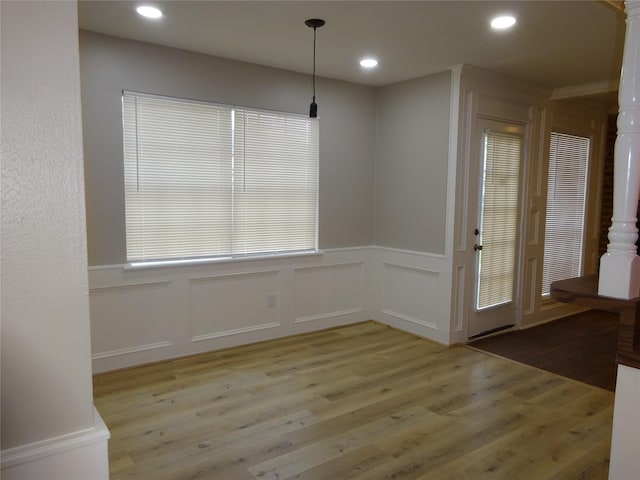 unfurnished dining area with wainscoting, recessed lighting, light wood-style flooring, and a decorative wall