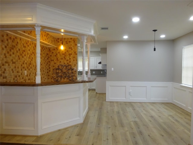 kitchen with visible vents, light wood finished floors, white cabinets, decorative light fixtures, and tasteful backsplash