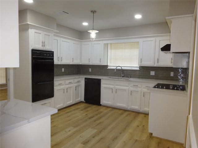 kitchen featuring black appliances, a sink, tasteful backsplash, white cabinetry, and light wood finished floors