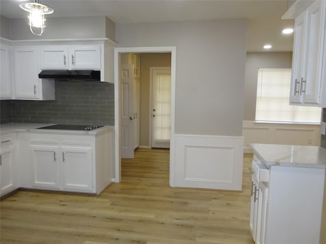 kitchen with white cabinetry, black electric stovetop, light wood-style floors, and under cabinet range hood