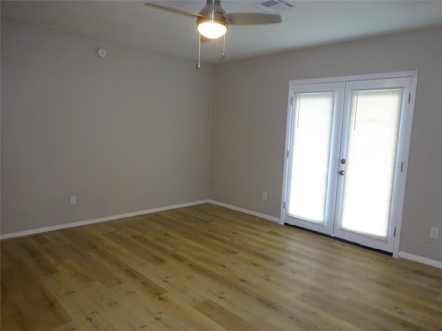 empty room featuring a ceiling fan, visible vents, baseboards, and light wood-type flooring