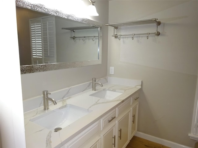 bathroom featuring double vanity, baseboards, and a sink