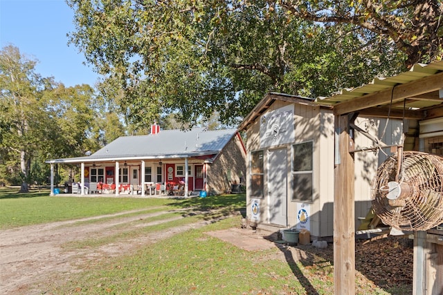 back of house featuring metal roof, a lawn, and a patio area