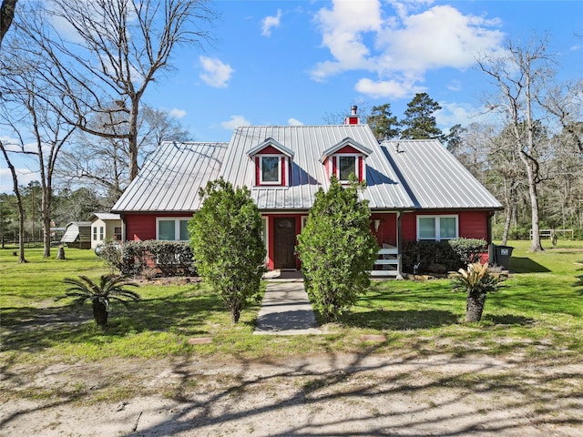 view of front of house featuring metal roof and a front yard