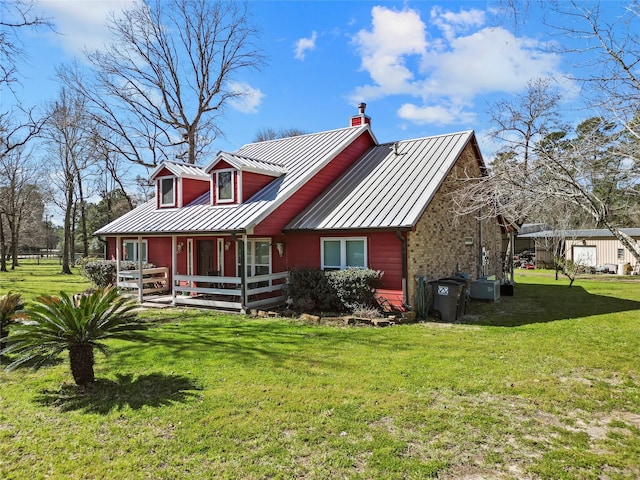 rear view of house featuring a yard, metal roof, and a standing seam roof