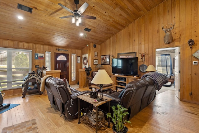 living room featuring visible vents, light wood-style flooring, wood ceiling, and wood walls