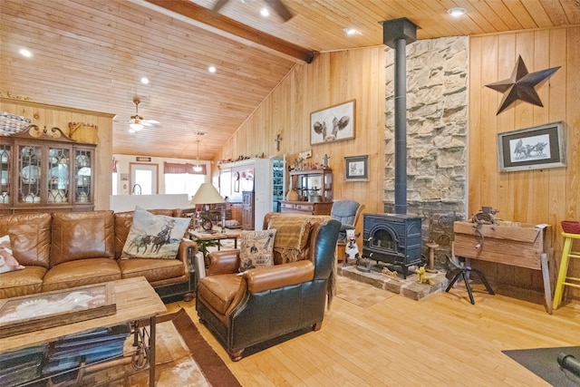 living room featuring high vaulted ceiling, wood finished floors, wooden ceiling, wood walls, and a wood stove