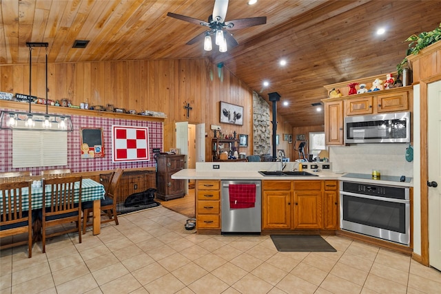 kitchen featuring a sink, stainless steel appliances, a peninsula, light countertops, and lofted ceiling