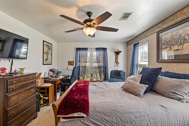 bedroom featuring visible vents, light carpet, a textured ceiling, and ceiling fan