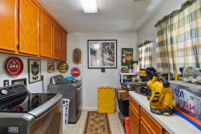 laundry area with independent washer and dryer, a textured ceiling, cabinet space, light tile patterned floors, and baseboards