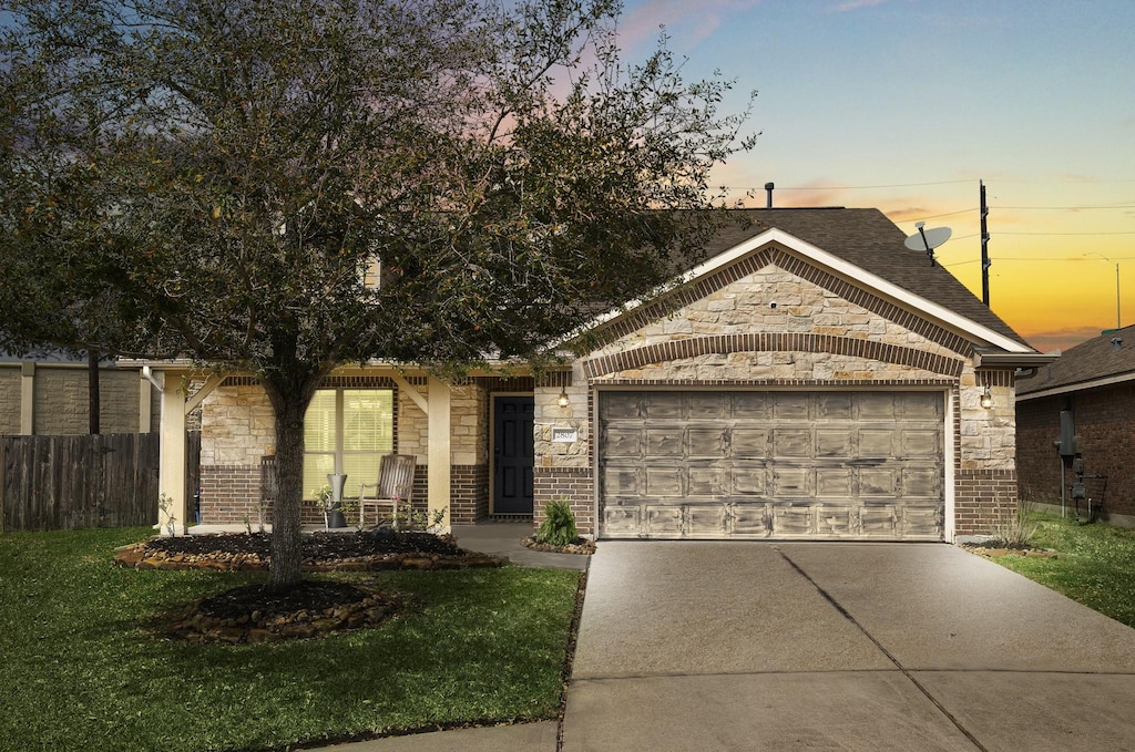 view of front of property featuring a front yard, fence, driveway, a garage, and brick siding