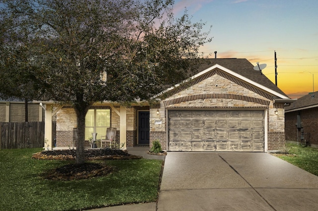 view of front of property featuring a front yard, fence, driveway, a garage, and brick siding