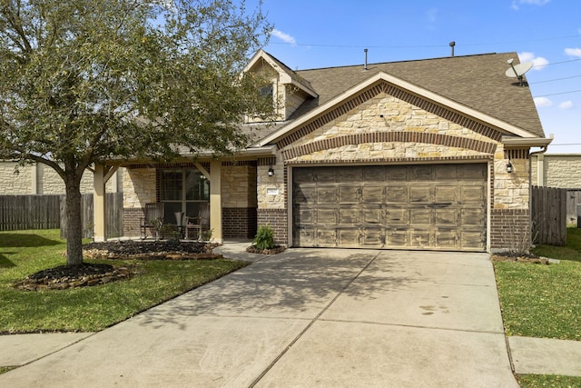 view of front of house featuring a front lawn, driveway, stone siding, fence, and an attached garage